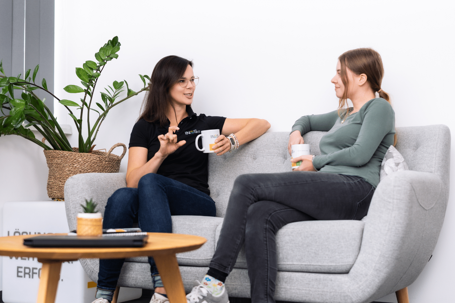 Zwei Frauen sitzen auf der Couch und unterhalten sich