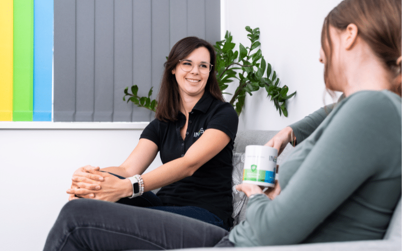 Zwei Frauen sitzen auf der Couch und unterhalten sich.