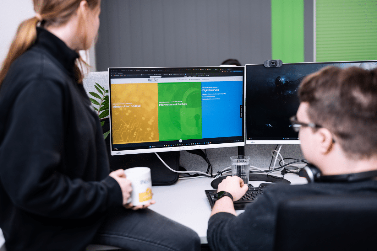 Eine Frau und ein Mann schauen auf den Bildschirm eines PCs